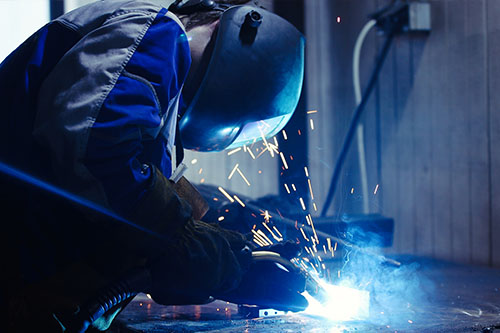 Työntekijä hitsaamassa hitsausmaski päässä